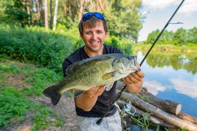 fisherman holding up a large bass fish he caught near asheville